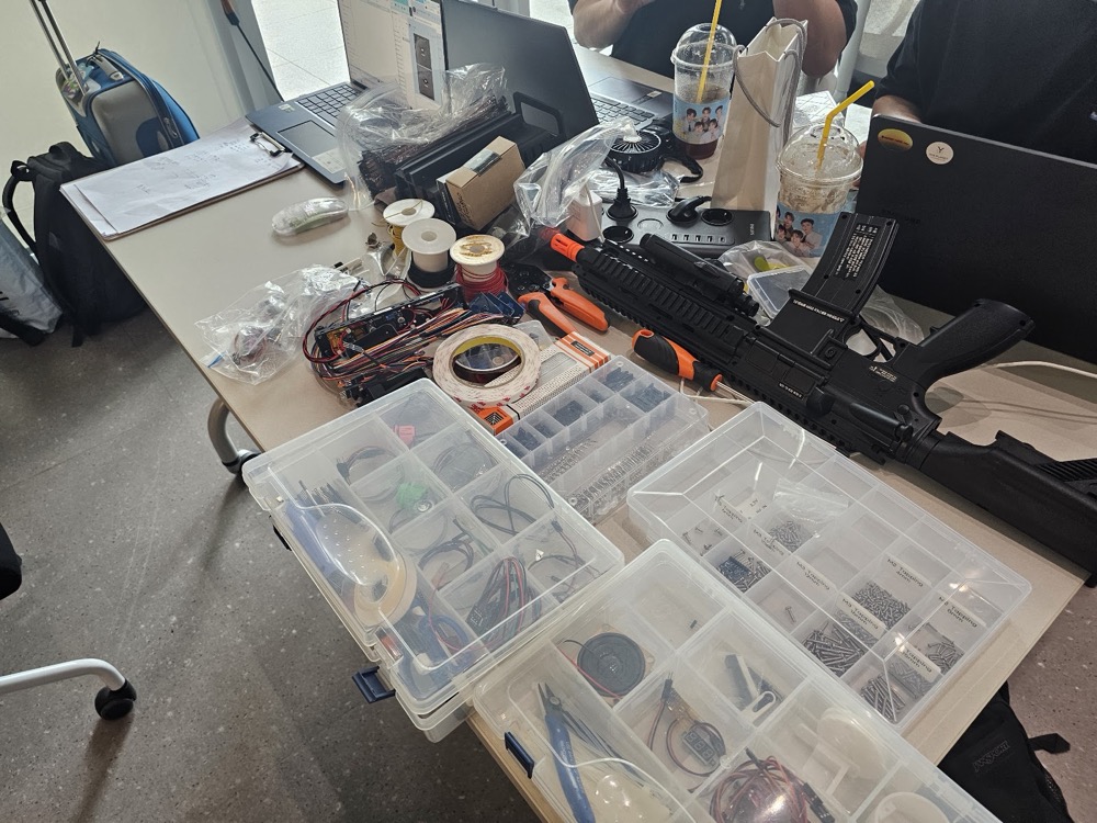 A workbench of sensors, servos and printed parts, a finished blaster resting on top